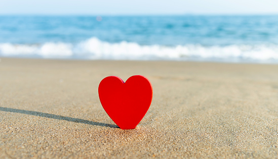 Single red heart on beach.