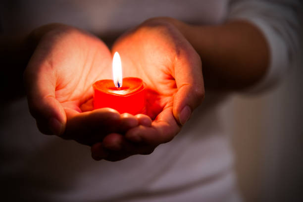 manos de mujer sosteniendo vela ardiente en forma de corazón - vela equipo de iluminación fotografías e imágenes de stock