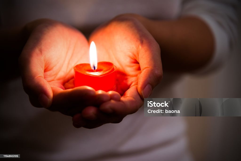 Woman hands holding burning heart-shaped candle Woman hands holding burning heart-shaped candle. Symbol of hope, peace and love. Candle Stock Photo