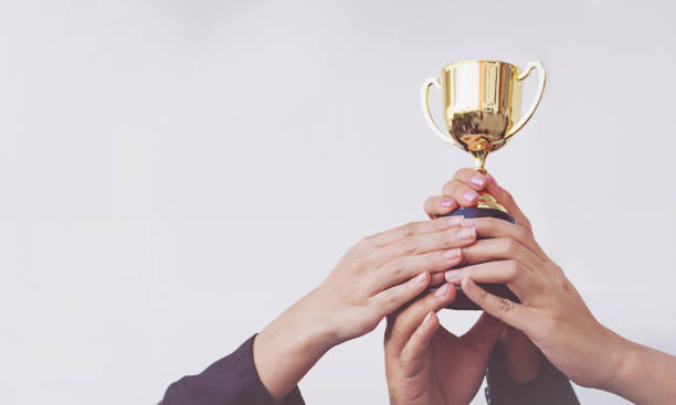 hand van team business holding een gouden trofee, concept teamwork - trophy stockfoto's en -beelden