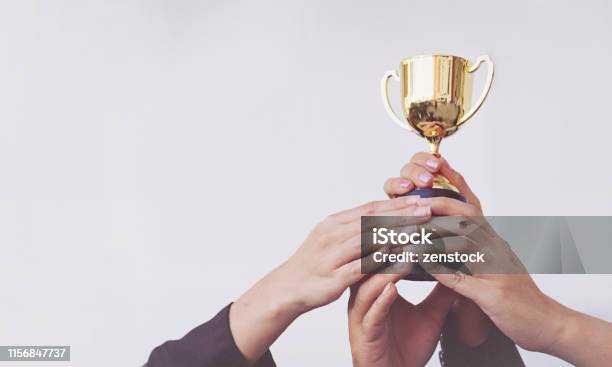 Foto de Mão Do Negócio Da Equipe Que Prende Um Troféu Dourado Trabalhos De Equipa Do Conceito e mais fotos de stock de Prêmio