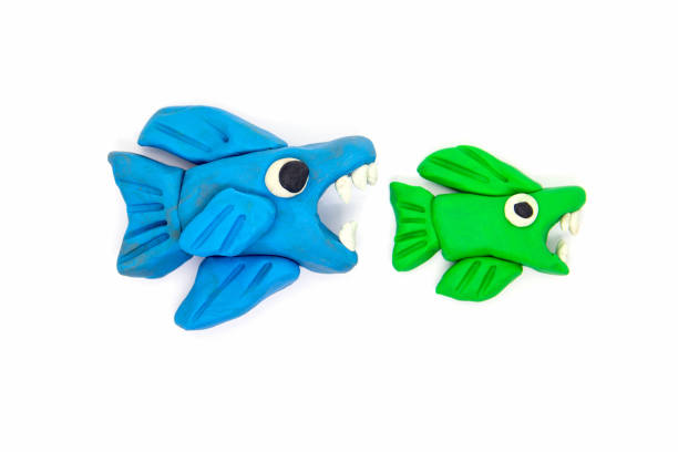istock Play dough big fish eat little fish on white background 1156847877
