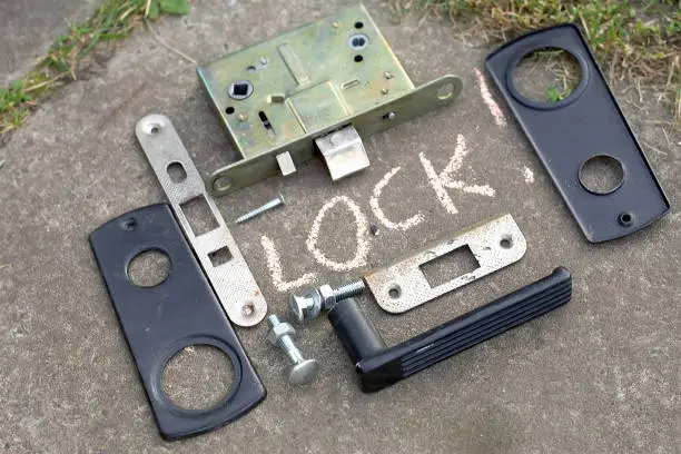 Close-up of a disassembled door lock placed on the ground, concept of safety