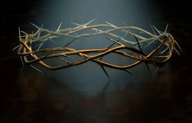 Branches of thorns woven into a gold crown depicting the crucifixion on a dark spotlit background - 3D render