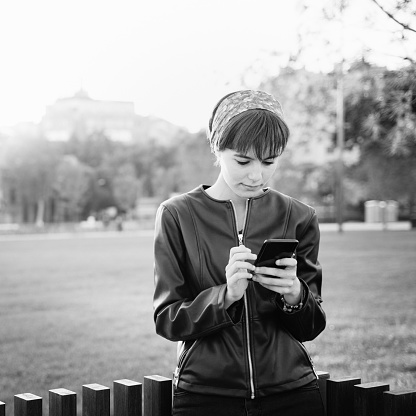 Young woman using phone in a park B&W