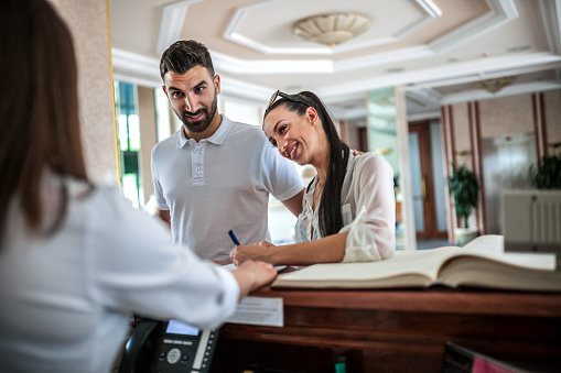 Couple talking to receptionist at hotel lobby