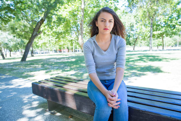 istock Serious pretty young lady sitting and relaxing in park 1156864909