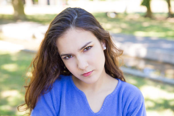 istock Serious pretty young woman looking at camera in park 1156864930