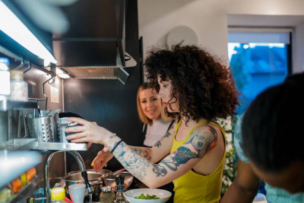 Young flatmates in the kitchen preparing dinner Young flatmates by the kitchen counter preparing dinner roommate stock pictures, royalty-free photos & images