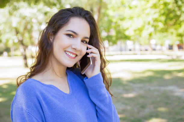 istock Positive young woman using mobile phone in park 1156865615