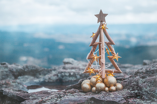 Rustic timber Christmas tree with gold star lights and baubles with Blue Mountains backdrop.  Seasonal holiday image, Christmas in July or Christmas in Blue Mountains, shallow dof, copy space.