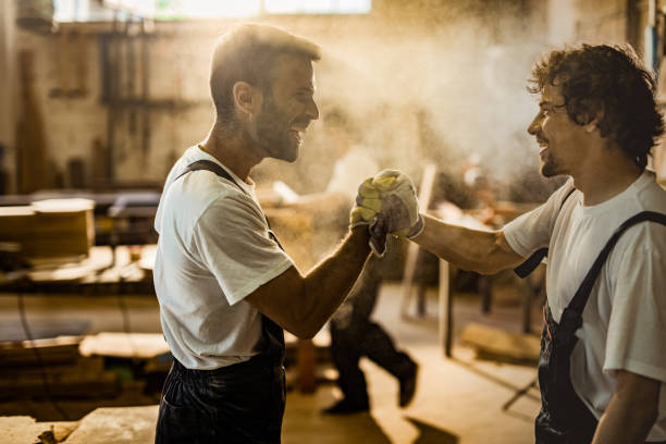 istock Two cheerful carpenters giving each other a manly greet in a workshop. 1156870557