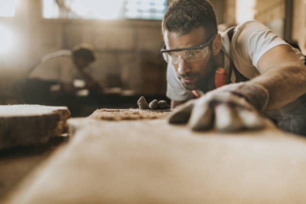 istock Young carpenter working on a piece of wood in a workshop. 1156870928