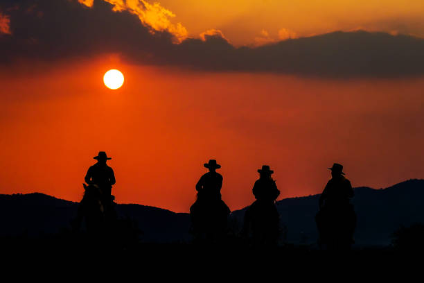 Cowboy riding a horse near the sun stock photo