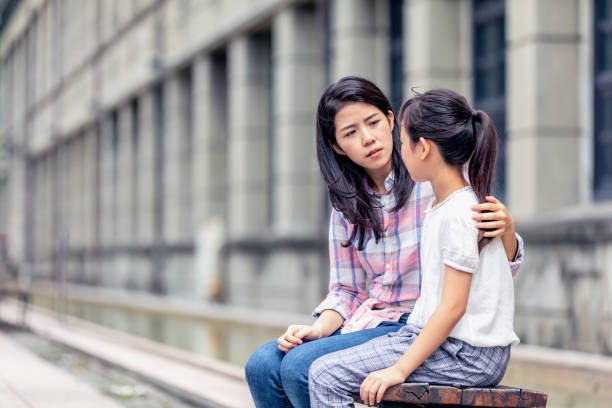 A mother having a serious talk with her daughter A woman is holding her arm around a young girl and is looking serious. pre adolescent child stock pictures, royalty-free photos & images
