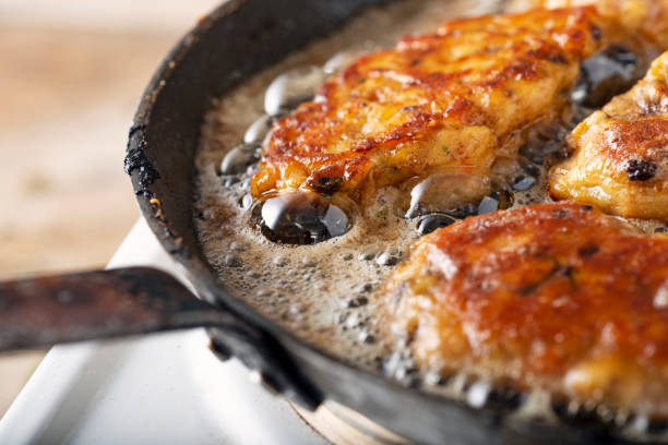 Traditional Danish Fiskefrikadeller or fish cakes, frying in a pan. Fiskefrikadeller are made from finely chopped white fish, usually cod  or haddock, with small pieces of more roughly chopped salmon added, along with cream, onion, carrot and  flour, salt and white pepper. Served with slices of lemon and remoulade. Colour, horizontal with some copy space.