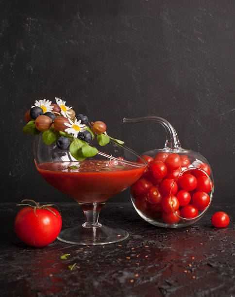 tomato smoothie or juice in an unusual beautiful glass decorated with lettuce, gooseberry and basil. the background of black slate or shale. copy space - basil tomato soup food and drink imagens e fotografias de stock