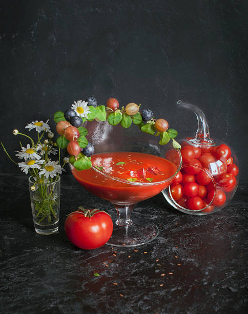 tomato smoothie or juice in an unusual beautiful glass decorated with lettuce, gooseberry and basil. the background of black slate or shale. copy space - basil tomato soup food and drink imagens e fotografias de stock