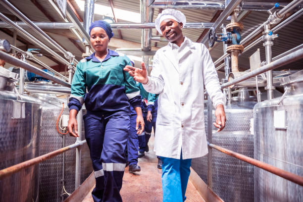 lavoratrice in fabbrica che cammina con il suo supervisore in una fabbrica - color image food dairy product people foto e immagini stock