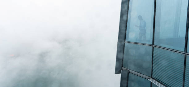 istock Businessman standing in a skyscraper building viewing over the city 1156874968