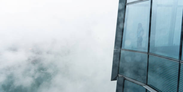 businessman standing in a skyscraper building viewing over the city - hong kong city urban scene building exterior imagens e fotografias de stock