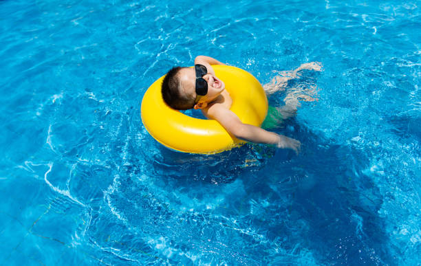 маленький мальчик, плавающий в бассейне - water park inflatable ring water swimming pool стоковые фото и изображения