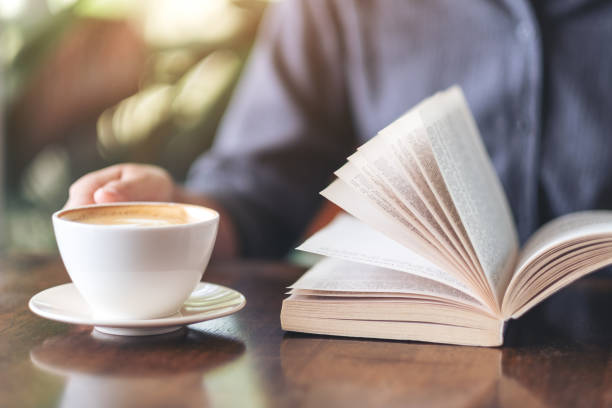 istock a woman holding and reading a vintage novel book 1156876143