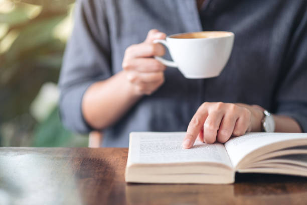 istock a woman pointing and reading a book while drinking coffee 1156876190