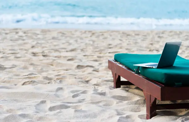 Photo of Laptop alone on empty oceanfront beach chair