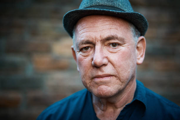 istock Slightly anxious looking senior man in hat by brick wall 1156881865