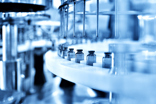 Close-up of the glass bottle filling at production line.