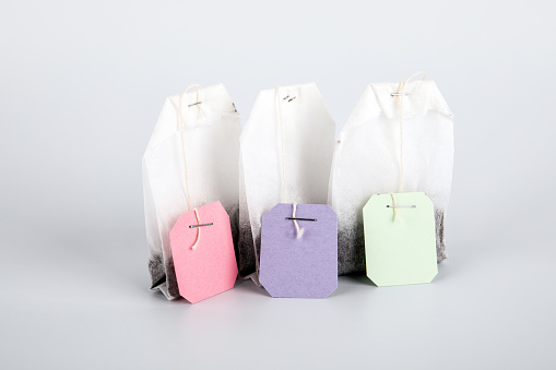Teabags with pink, green and purple label. Top view, on a white background. mockup