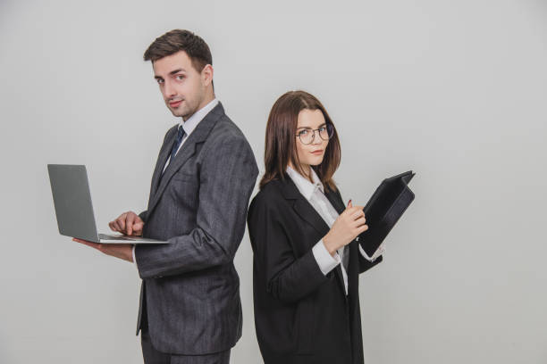 istock Busy successful work partners standing shoulder to shoulder, checking data, looking pleasantly at the camera. Man working with laptop, woman with tablet. 1156885890