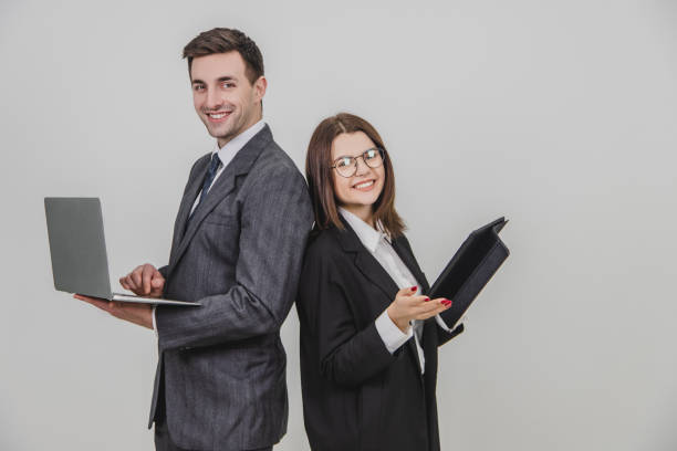 istock Busy successful work partners standing shoulder to shoulder, checking data, smiling with satisfaction on their faces. Man working with laptop, woman with tablet. 1156885893