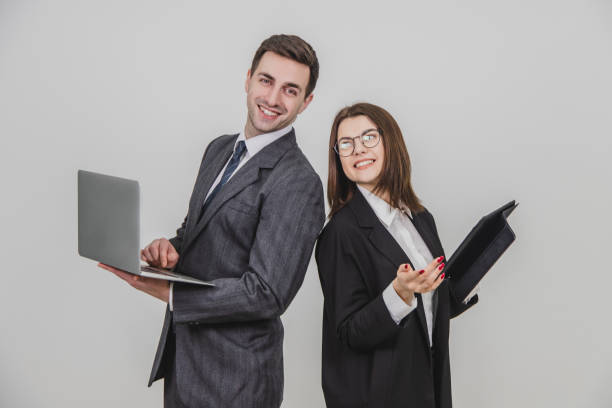 istock Busy successful work partners standing shoulder to shoulder, checking data, smiling with satisfaction on their faces. Man working with laptop, woman with tablet. 1156885991
