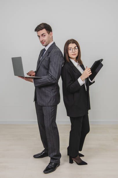istock Full-length busy successful work partners standing shoulder to shoulder, checking data, looking at the camera, raising their eyebrows. Man working with laptop, woman with tablet. 1156886017
