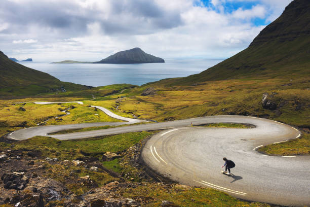 молодая фигуристка катается на скейтборде по удовлетворительным пейзажам фарерских островов - downhill skiing стоковые фото и изображения