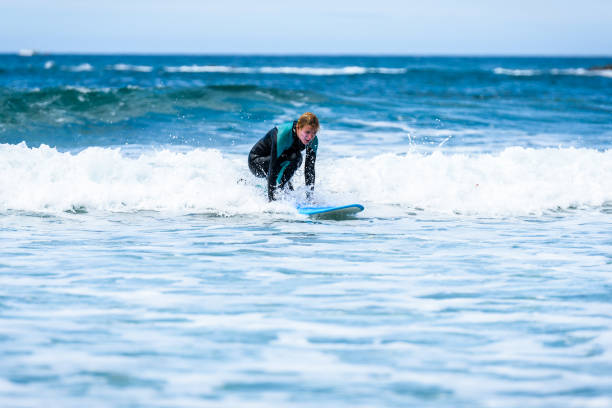 istock Surfer girl surfing with surfboard on waves in Atlantic ocean. 1156893036