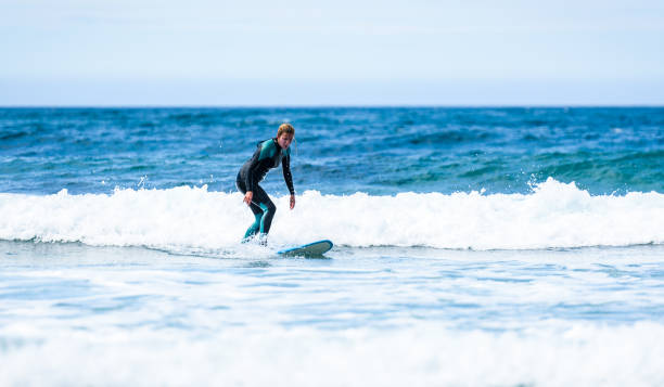 istock Surfer girl surfing with surfboard on waves in Atlantic ocean. 1156893046