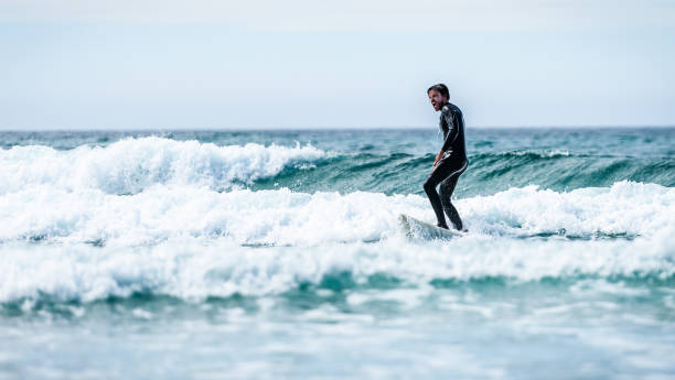 istock Surfer guy surfing with surfboard on waves in Atlantic ocean. 1156893183