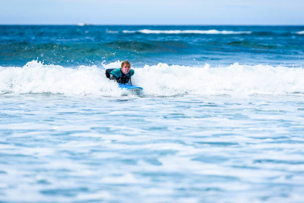 istock Surfer woman with surfboard is paddling on the wave. 1156893903
