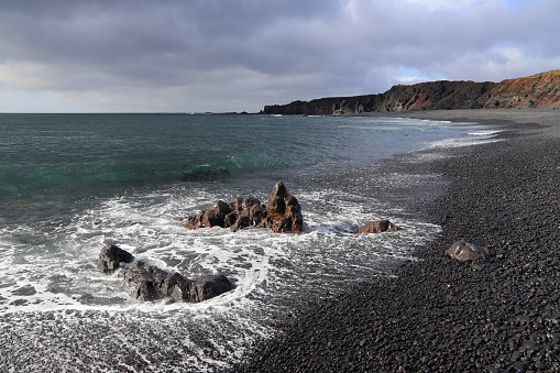 A scenic view of the Djupalonssandur beach. The Djupalonssandur or the Black Lava Pearl Beach located near Snaefellsjokull on the southern coast of Snaefellsnes peninsula in West Iceland.