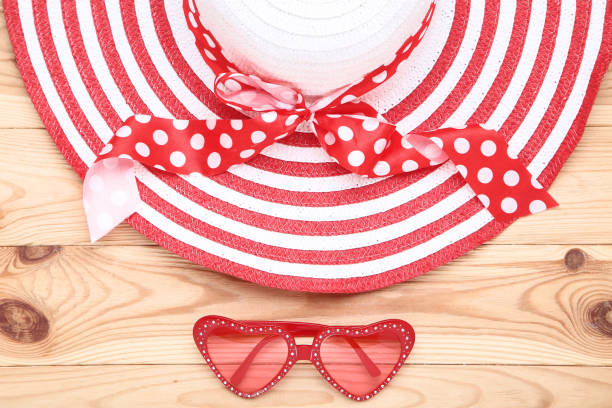 Beach hat with sunglasses on brown wooden table