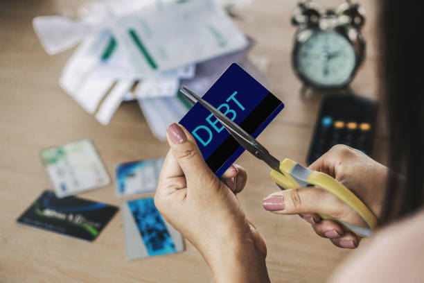 kobieta ręcznie cięcia kart kredytowych przez nożyczki z kalkulatorem i rachunki finansowe na biurku - debt zdjęcia i obrazy z banku zdjęć