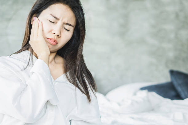 istock Asian woman suffering from toothache sitting on bed 1156900674