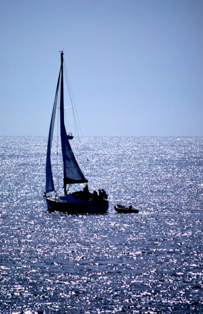 Sailing yacht against the sun on a sparkling blue sea