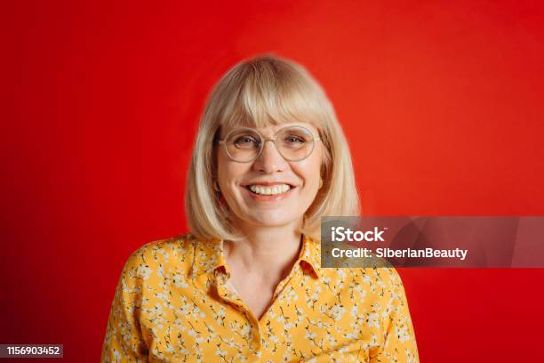 Smiling Mature Woman In Glasses On Red Background Stock Photo - Download Image Now - Red Background, People, One Person