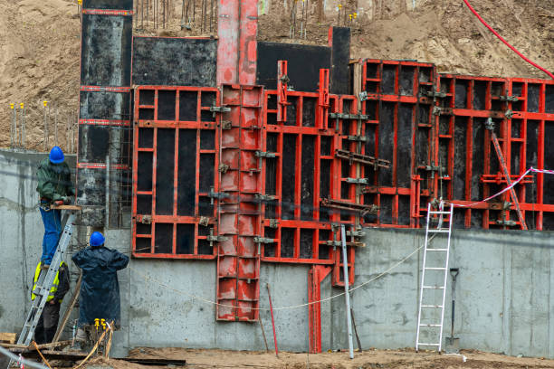 istock Builder working on construction foundation. Man in blue work clothes on the ladder brazing metal to strengthen concrete wall structure on the hill slope 1156904558