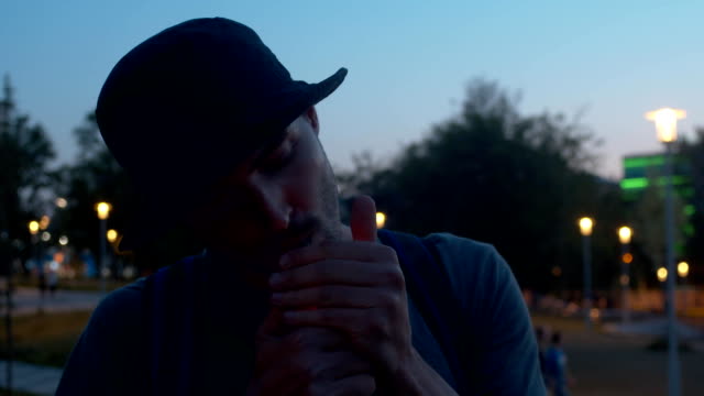 Portrait of a young man lights a cigarette