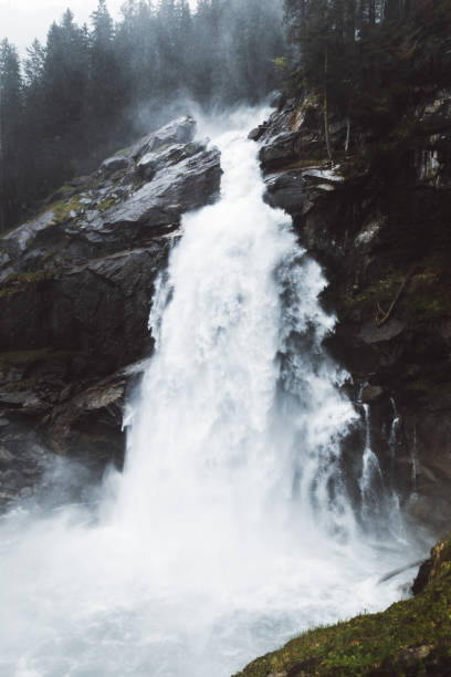 Dramatic view of one of the highest waterfalls in Europe during foggy summer day in Tyrol - the Alps